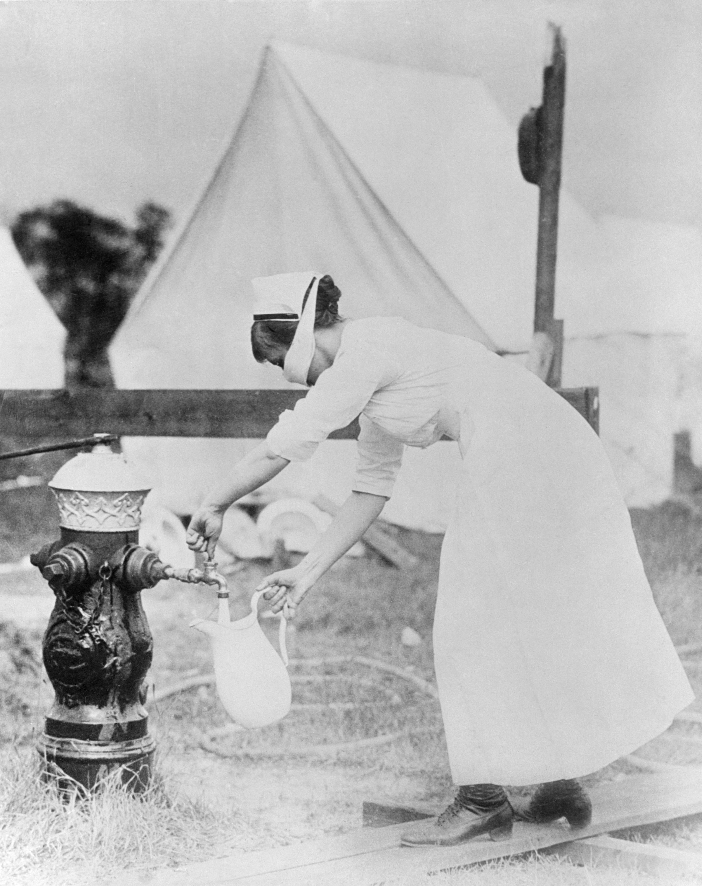 Masked nurse pumping water at a field hospital